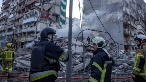 Reuters Emergency service workers search a smouldering building