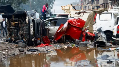 Reuters A man looks through the wreckage of private vehicles destroyed following heavy rainfall in the Grogan area of Nairobi