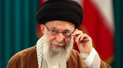 AFP via Getty Images Ayatollah Ali Khamenei adjusts his glasses in a 2024 photograph