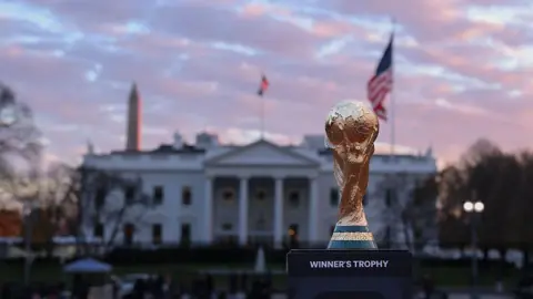 Getty Images The World Cup trophy sits in front of the White House with a USA flag and the Washington Monument either side of it. 