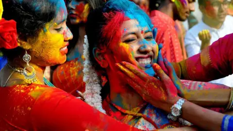Getty Images People react as fellow students throw colored powder in her face at the Holi or Color Festival Celebration near Kolkata, India, on March 13, 2025.
