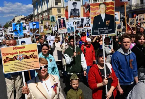 Reuters Crowds of people march along a road carrying placards featuring pictures of soldiers and veterans during an Immortal Regiment march in Vladivostok.