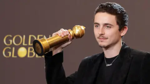 Reuters Timothee Chalamet holding up his Golden Globe