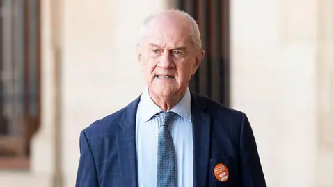 Gallo via Getty Images Roelf Meyer is seen in a blue suit and tie as he stands outside the Union Buildings