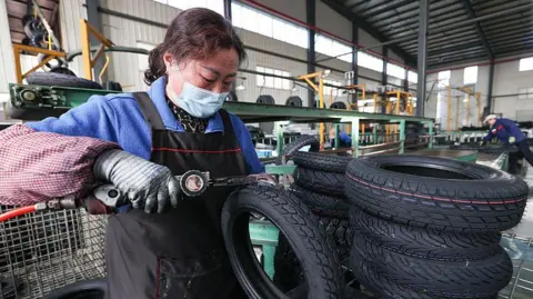 Getty Images A woman processes tyre orders at a vehicle factory in China