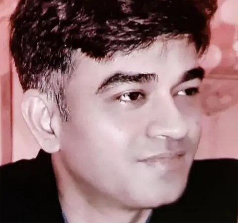 PTI Chandranath Rath head and shoulders portrait seen in a black shirt looking away from camera.