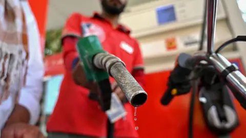 Getty Images An attendant at a petrol station refills a motorbike with fuel