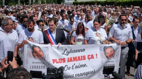 EPA A crowd of people carry a banner reading 'never again' and featuring a picture of Lyhanna during a protest outside
