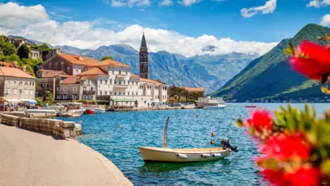 Getty Images Scenic panorama view of the historic town of Perast at famous Bay of Kotor with blooming flowers on a beautiful sunny day with blue sky and clouds in summer, Montenegro