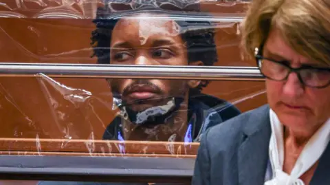 Getty Images US singer D4vd looks on from behind a clear screen as his defence attorney Marilyn Bednarski appears with him in court during his arraignment for the murder of Celeste Rivas Hernandez at Clara Shortridge Foltz Criminal Justice Center on 20 April 2026 in Los Angeles, California.