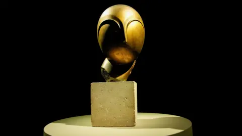 Reuters A bronze sculpture depicting a face sits on a table with a black background