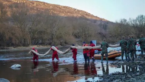 CNMC Moldova Men in red carry a boom into the water to prevent oil spilling in the River Dniester