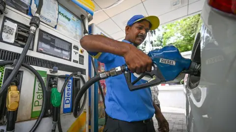 Hindustan Times via Getty Images An attendant at a petrol station is pictured filling a car with diesel in India.
