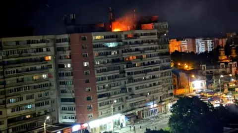 Reuters A small fire is seen on top of a multi-storey building at night 