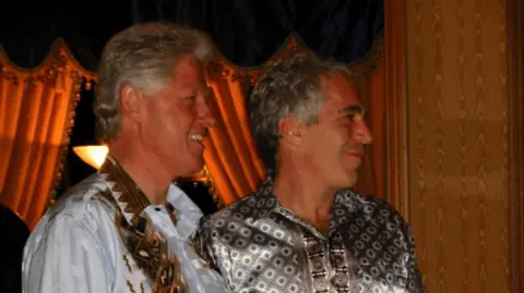 Reuters Clinton and Epstein stand next to each other smiling, both wearing shiny shirts