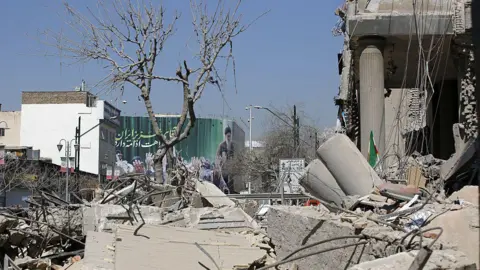 Fatemeh Bahrami/Anadolu via Getty Images A view of destruction on Enqelab Square following the attacks launched by the US and Israel on Tehran. Rubble and large slabs of concrete cover the ground. 