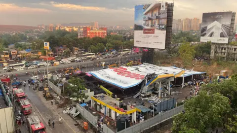 Reuters A huge ad billboard can be seen collapsed onto a petrol station and some housing in a suburb of Mumbai, India.