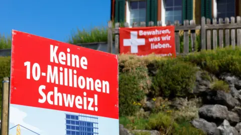 Reuters Signs stand in front of a building, on the day of the vote on a plan backed by the right-wing Swiss People's Party (SVP)