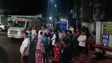 ANI Men and women gather near an ambulance outside the hospital building where the fire incident took place.