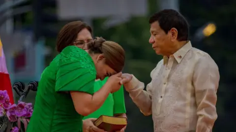 Getty Images Philippine Vice-President Sara Duterte kisses the hand of her father, former president Rodrigo Duterte
