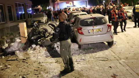 Getty Images A first responder gazes upwards at the site of a cluster bomb strike. 