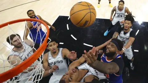 Geoff Burke-Pool Photo via Imagn Images New York Knicks center Mitchell Robinson (23) and San Antonio Spurs forward Victor Wembanyama (1) battle for the ball during game five of the 2026 NBA Finals at Frost Bank Center. 