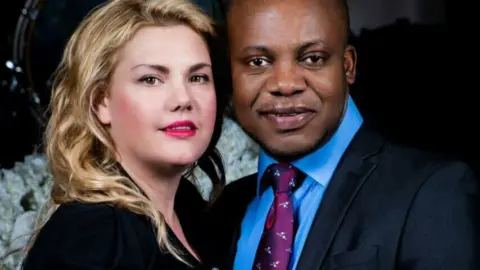 Facebook Close-up portrait of a man and woman standing together, both dressed in formal clothing and facing the camera.