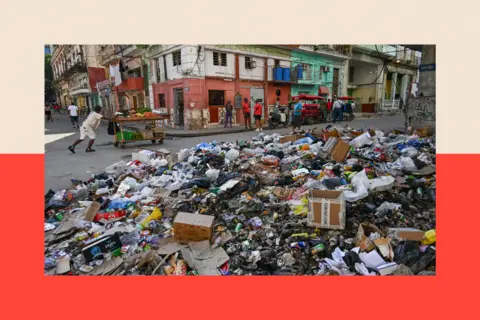 AFP via Getty Images People walk past rubbish piled up on a street in Havana