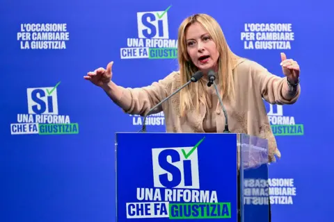 Getty Images Giorgia Meloni is speaking at a podium with the words 