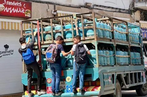 Wilfrid Esteve/AFP Schoolchildren cling to the back of a truck delivering gas cylinders in Tangier, Morocco - Saturday 11 May 2024