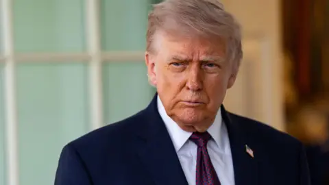 EPA Donald Trump looks off to the side of the camera wearing a dark suit with an American flag badge