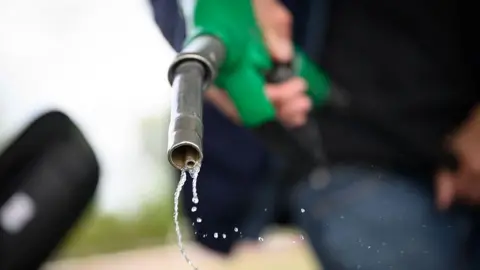 AFP via Getty Images Petrol drips out of a fuel hose at a petrol station in Saint-Etienne-de-Montluc, western France, on 15 April, 2026.