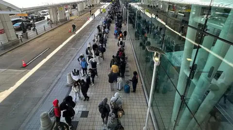Getty Images People in a line outside the airport