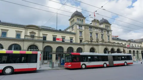 Getty Images A wide shot of of Winterthur train station taken on a spring day in 2019. Two buses are waiting outside the station.