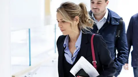 Getty Images A woman in a ponytail wearing a suit arrives in court 