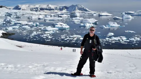 Facebook Man standing on snow in black outfit with snow-covered water in background behind him