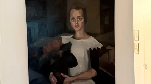 Arthur Brand A painting believed to be Toon Kelder's 'Portrait of a Young Girl' shows a girl in a white dress with black sleeves holding what appears to be a bouquet of red flowers. She has brown hair and blue eyes and is sitting.