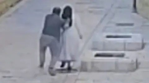 Israel Police Grainy image from CCTV of a man from behind reaching out to push a nun as both walk in a street in Jerusalem (28/04/26)