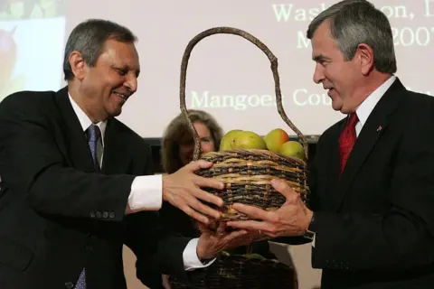 AFP via Getty Images Indian Ambassador Ronen Sen (L) hands a basket of Indian mangoes to US Agriculture Secretary Mike Johanns at a ceremony celebrating the opening of mango trade between the United States and India at the Commerce Department in Washington 01 May 2007. 