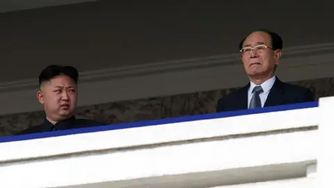 Getty Images Kim Jong Un standing on a balcony glancing at his side towards Kim Yong Nam