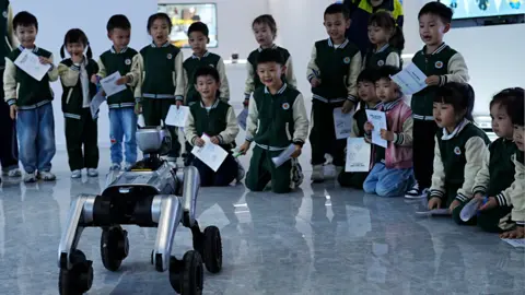 Children laugh as they watch the robots perform.