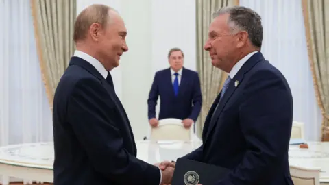 Sputnik/Gavriil Grigorov/Pool via REUTERS Putin and Witkoff shaking hands in a gilded room