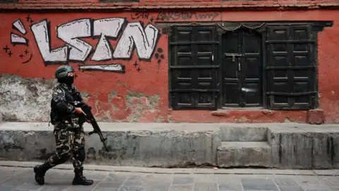 Reuters A member of the Nepali army patrols a street ahead of the House of Representatives elections scheduled for March 5, 2026, following the deadly "Gen Z" led anti-graft protests in September that toppled the government, in Lalitpur, Nepal. A red wall can be seen behind him with grafiti saying "lstn"