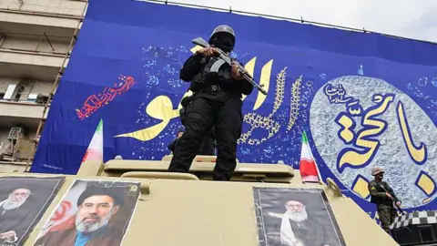 AFP Members of the security forces stand guard on armoured vehicles plastered with portraits of Iran's slain supreme leader Ayatollah Ali Khamenei (L and R) and of his son, Iran's new supreme leader Ayatollah Mojtaba Khamenei.