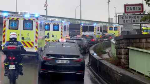 Getty Images Ambulances transporting French national passengers of the MV Hondius drive along a highway into Paris.