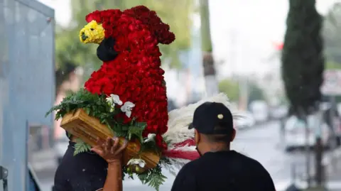 Francisco Guasco/EPA/Shutterstock A person carries a floral arrangement during the wake of Nemesio Oceguera Cervantes, alias El Mencho, leader of the Jalisco New Generation Cartel (CJNG), in Guadalajara, Mexico, 01 March 2026 (Issued 02 March 2026). 