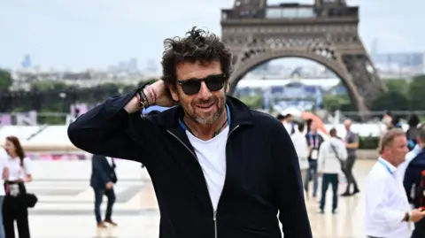 Reuters File pic showing Patrick Bruel in a black cardigan, black hair and a white T-shirt