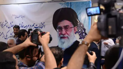 Hulton Archive via Getty Images Ayatollah Khamenei shown on a poster. Supporters are photographing it.