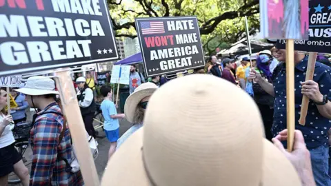 Getty Images Protesters hold signs that say "Hate Won't Make America Great" as they march in Houston