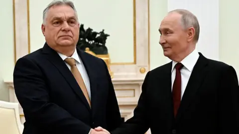 POOL/AFP via Getty Images Two men in black suits shake hands